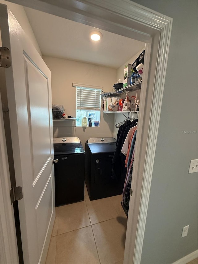 clothes washing area with laundry area, washing machine and clothes dryer, and light tile patterned floors