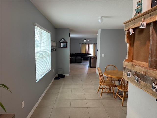 dining room featuring a textured ceiling, light tile patterned flooring, a ceiling fan, and baseboards