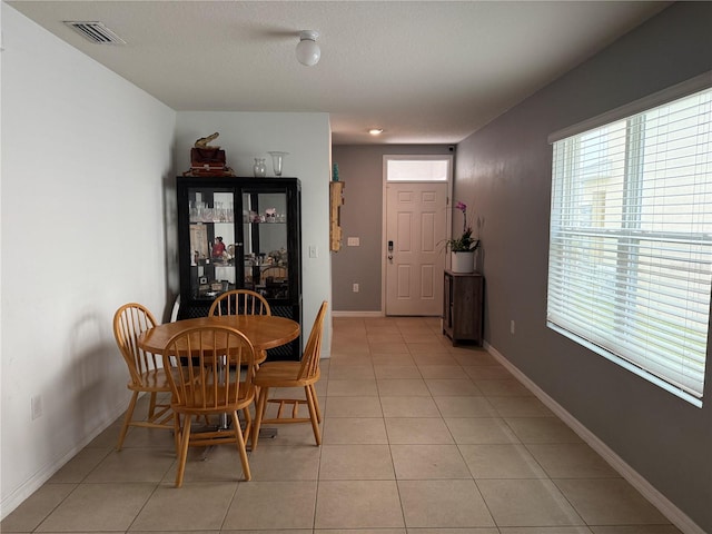 dining space featuring light tile patterned flooring, visible vents, and baseboards