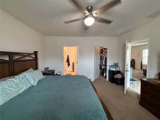 bedroom featuring light colored carpet, visible vents, a ceiling fan, connected bathroom, and a textured ceiling