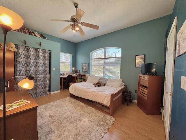 bedroom with baseboards, a textured ceiling, a ceiling fan, and wood finished floors