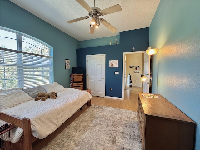 bedroom with a textured ceiling, a ceiling fan, and light wood finished floors