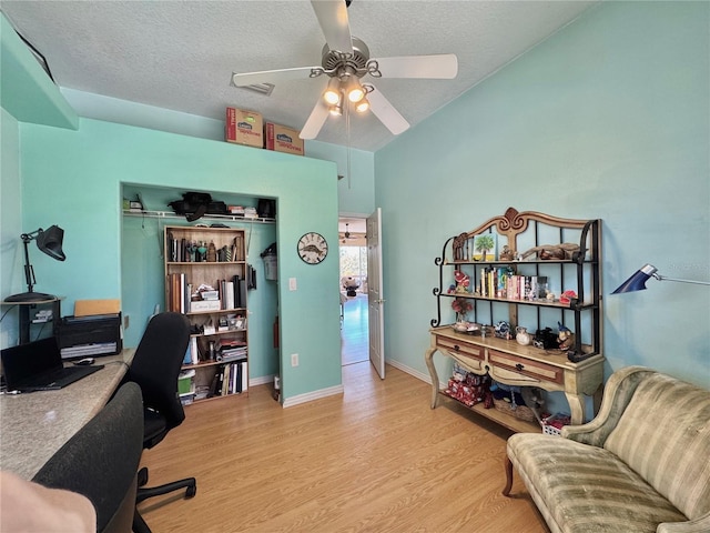 office featuring baseboards, a textured ceiling, light wood-type flooring, and ceiling fan