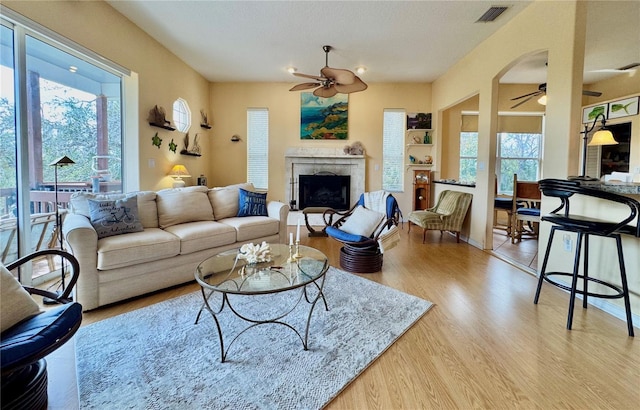 living area featuring a wealth of natural light, visible vents, a ceiling fan, and wood finished floors