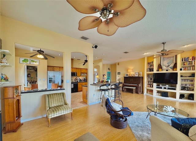 living area featuring a ceiling fan, visible vents, and light wood finished floors