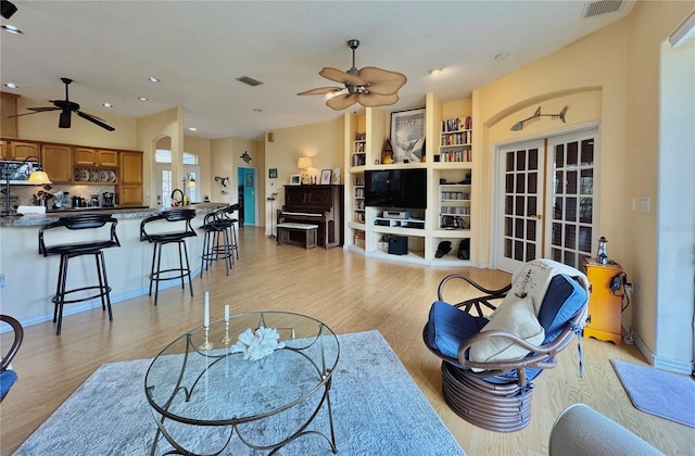 living room with visible vents, baseboards, light wood-style flooring, and a ceiling fan