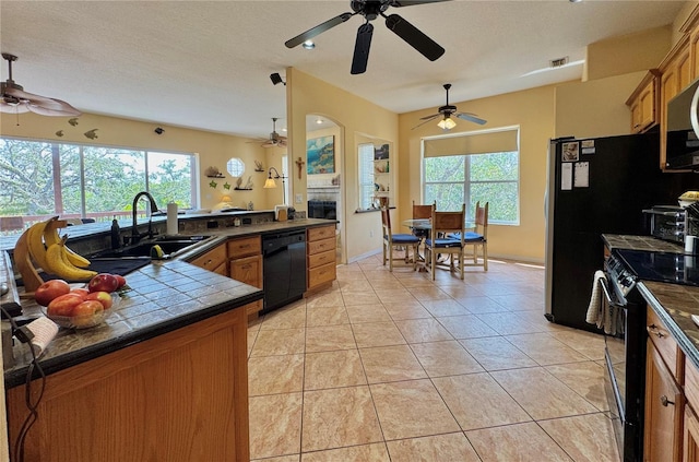 kitchen with brown cabinetry, black appliances, ceiling fan, and a sink