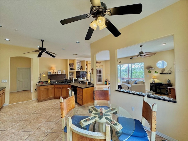 dining area featuring arched walkways, baseboards, a ceiling fan, and light tile patterned flooring