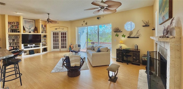 living area featuring visible vents, wood finished floors, ceiling fan, and a fireplace