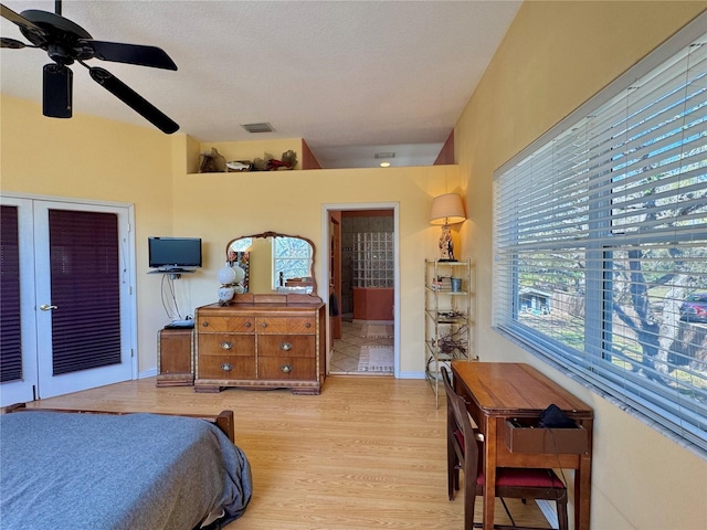 bedroom with visible vents, baseboards, ensuite bathroom, wood finished floors, and a ceiling fan