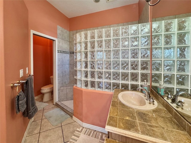 bathroom featuring baseboards, a sink, a walk in shower, tile patterned floors, and toilet