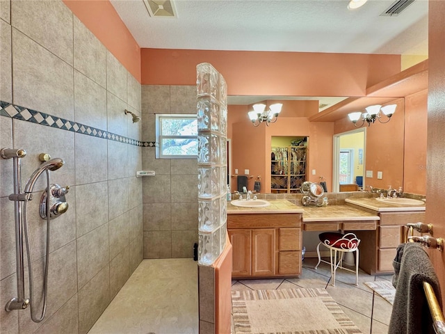 full bathroom with visible vents, double vanity, a sink, a walk in shower, and a chandelier