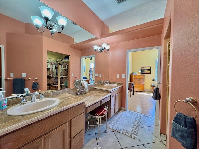 full bath with tile patterned flooring, double vanity, a notable chandelier, and a sink