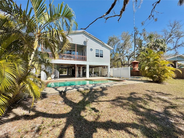 rear view of house with stairway, a balcony, fence, a fenced in pool, and a patio area