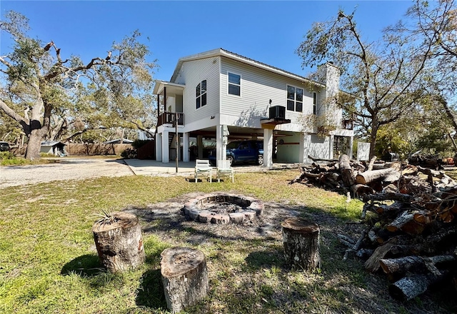 rear view of house with a fire pit, stairway, concrete driveway, a carport, and a patio