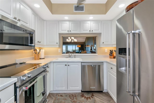 kitchen with visible vents, a sink, stainless steel appliances, light countertops, and white cabinetry