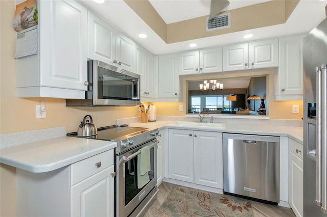 kitchen featuring visible vents, white cabinetry, stainless steel appliances, and a sink