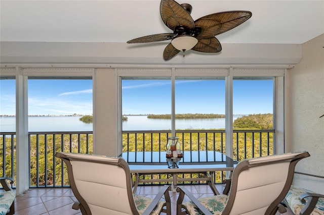 sunroom with plenty of natural light, ceiling fan, and a water view