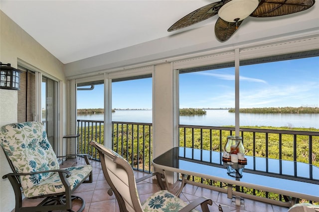 sunroom with plenty of natural light, ceiling fan, and a water view