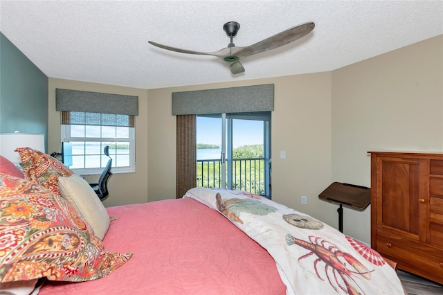 bedroom featuring multiple windows, a textured ceiling, a ceiling fan, and access to outside