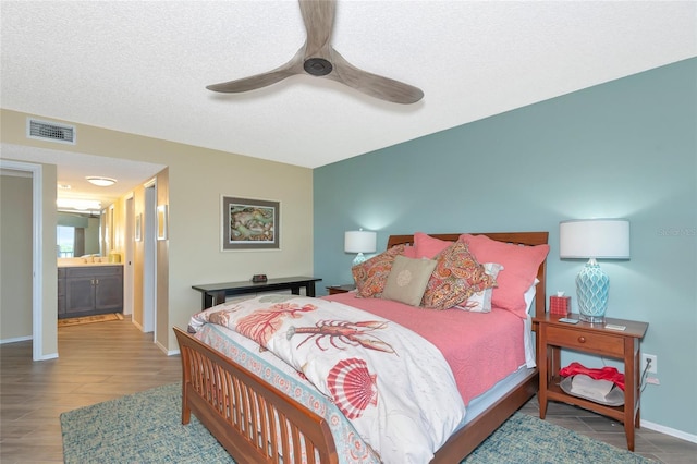 bedroom with visible vents, a ceiling fan, a textured ceiling, wood finished floors, and baseboards