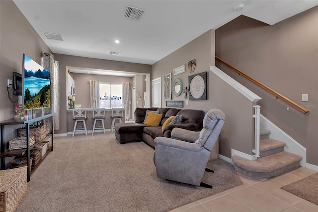 carpeted living area featuring stairway, tile patterned flooring, visible vents, and baseboards