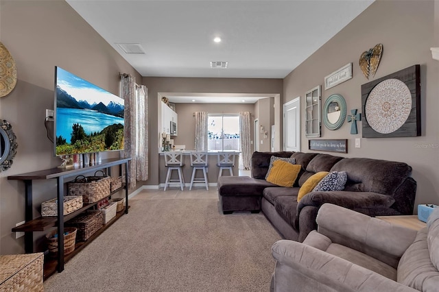 living room featuring light tile patterned floors, baseboards, visible vents, and light colored carpet