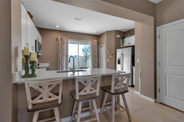 kitchen with light tile patterned floors, light countertops, appliances with stainless steel finishes, a sink, and a peninsula