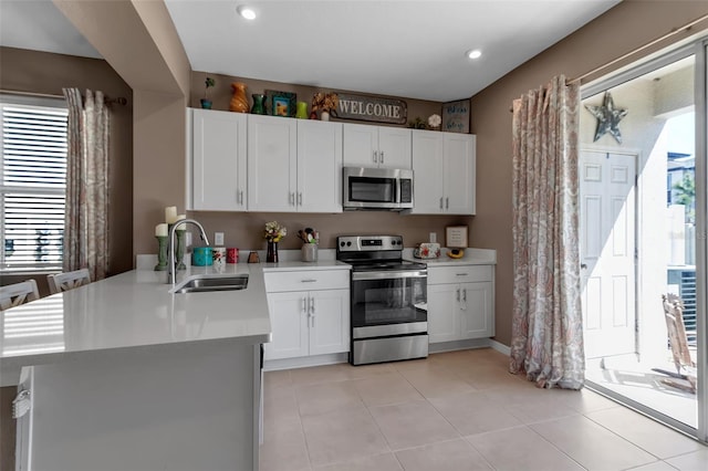 kitchen featuring stainless steel appliances, a sink, light countertops, and white cabinets