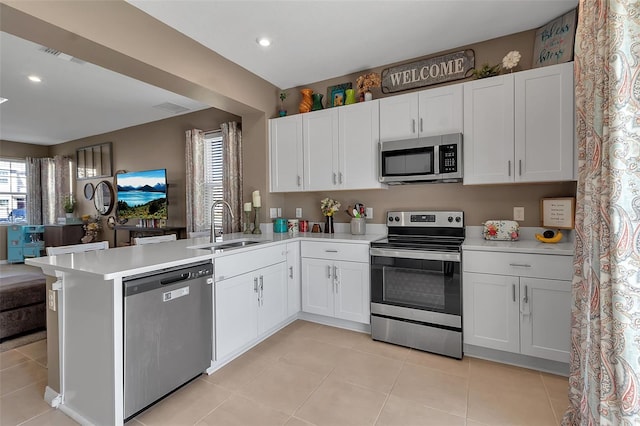 kitchen featuring a peninsula, stainless steel appliances, a sink, and light countertops