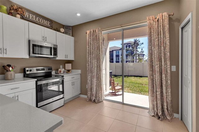 kitchen with white cabinets, stainless steel appliances, light countertops, and light tile patterned flooring