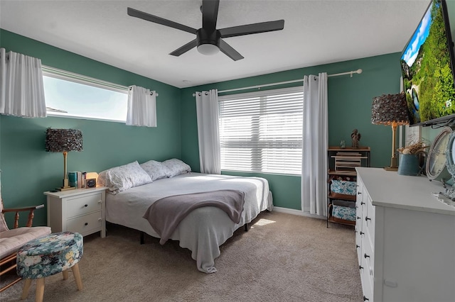 bedroom with a ceiling fan, light colored carpet, and multiple windows