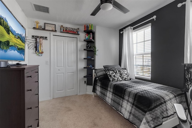 carpeted bedroom featuring ceiling fan, visible vents, and a closet