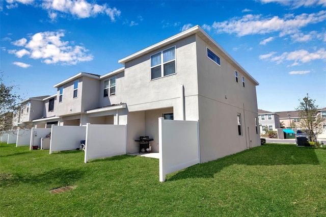 back of house featuring a yard, fence, and stucco siding