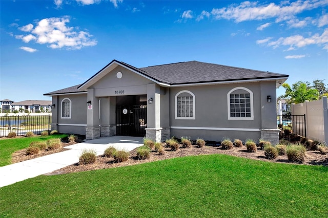 view of front of home with stucco siding, roof with shingles, fence, and a front yard