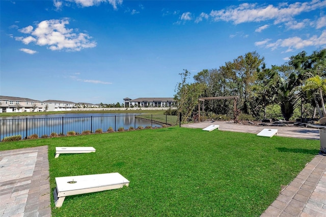 view of community featuring a lawn, a water view, and fence