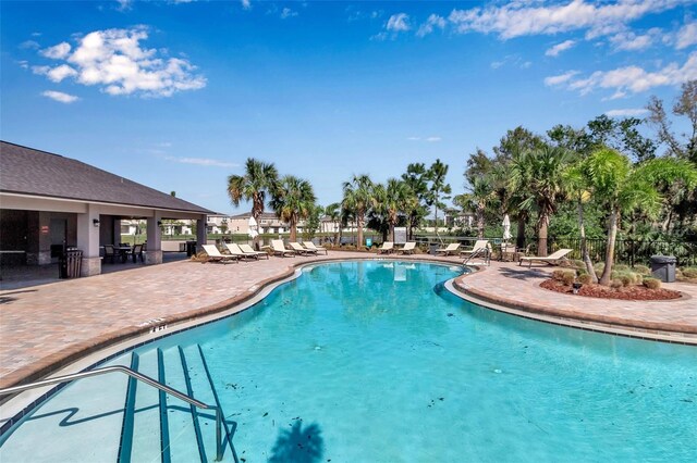 community pool featuring fence and a patio