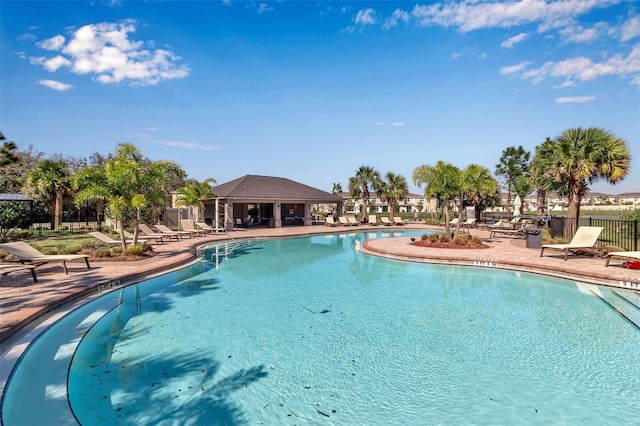 community pool with a patio area and fence