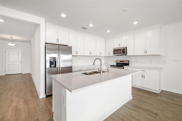 kitchen featuring wood finished floors, visible vents, a sink, decorative backsplash, and appliances with stainless steel finishes