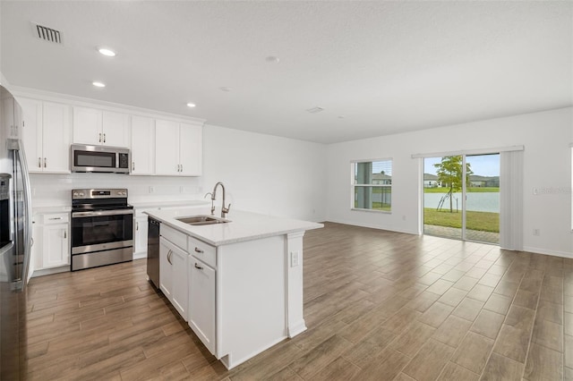 kitchen featuring visible vents, a sink, stainless steel appliances, light countertops, and open floor plan