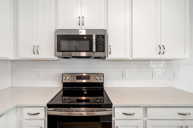 kitchen with tasteful backsplash, stainless steel microwave, white cabinetry, and electric range