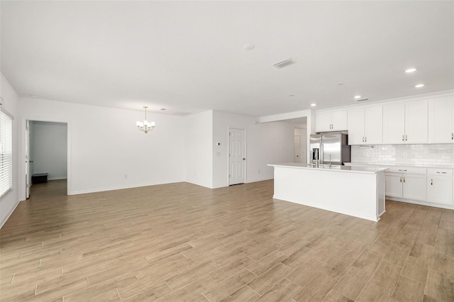 kitchen featuring decorative backsplash, stainless steel fridge, light wood-style floors, and white cabinets