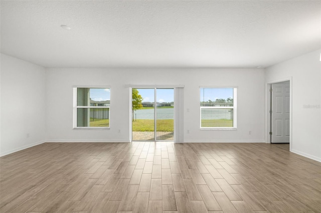 unfurnished room featuring wood finished floors, baseboards, and a textured ceiling