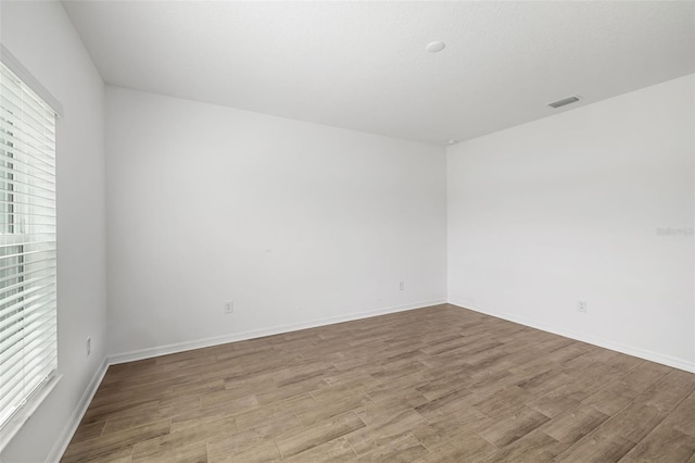 empty room with visible vents, baseboards, and wood finished floors