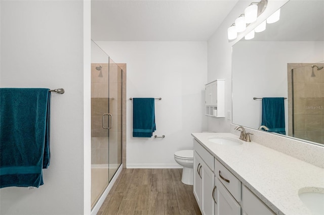 full bathroom featuring toilet, a sink, wood finished floors, a shower stall, and double vanity