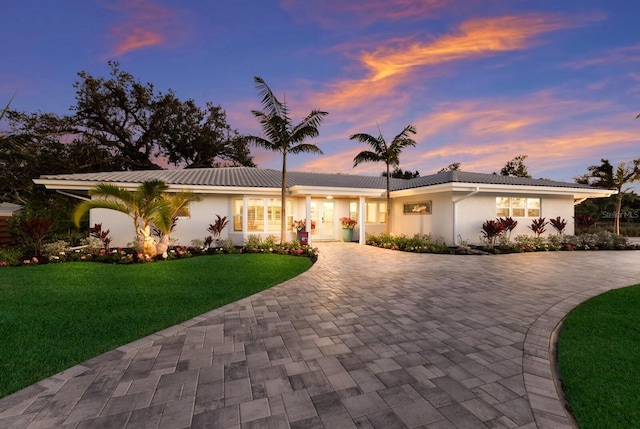 ranch-style house with driveway, a front lawn, and stucco siding