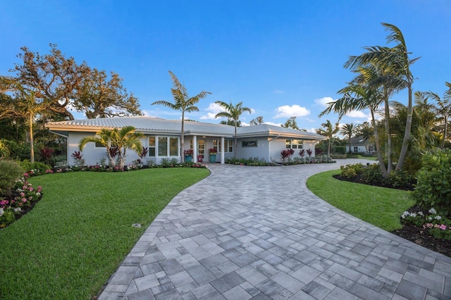 single story home with decorative driveway, a front yard, and stucco siding