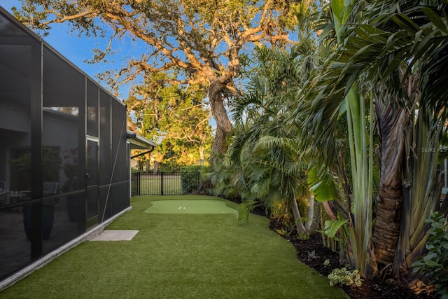 view of yard with glass enclosure and fence