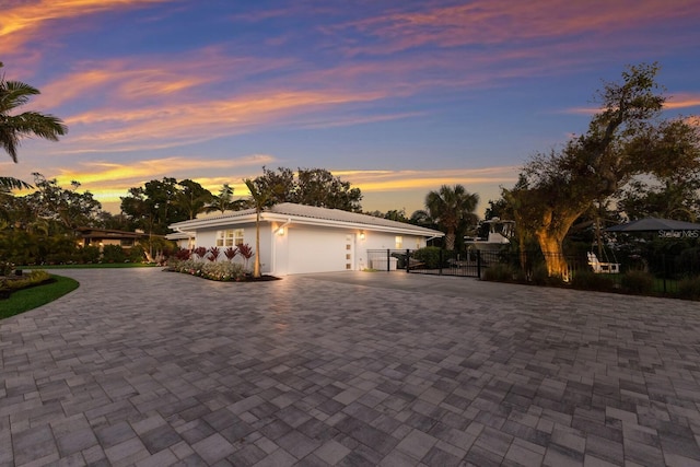 view of front of property featuring decorative driveway, an attached garage, fence, and stucco siding