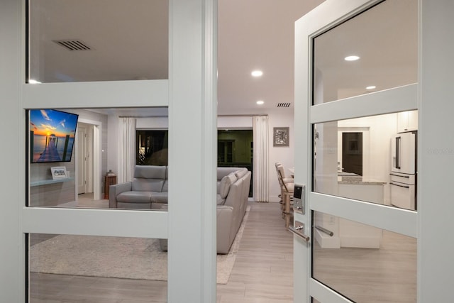 hallway with recessed lighting, visible vents, and light wood finished floors